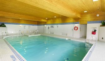 The hotel’s indoor pool is brightly lit and has chairs by the side.