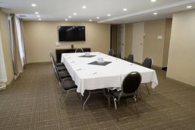 Meeting room in Les Suites Hotel Ottawa, with long table, ten chairs around it, and a large television.