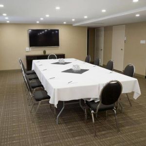 Meeting room in Les Suites Hotel Ottawa, with long table, ten chairs around it, and a large television.