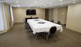 Meeting room in Les Suites Hotel Ottawa, with long table, ten chairs around it, and a large television.