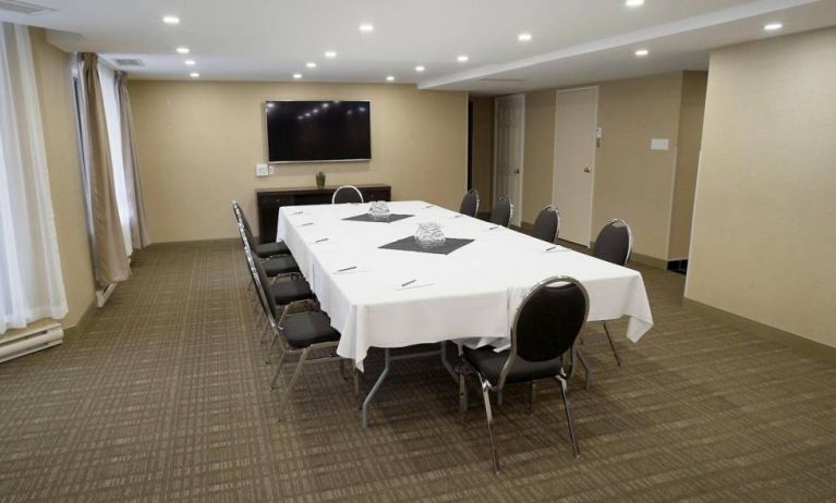 Meeting room in Les Suites Hotel Ottawa, with long table, ten chairs around it, and a large television.