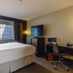 Guest room in Arc The Hotel Ottawa, with a workspace desk and chair, plus armchair and sofa.