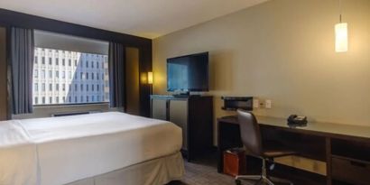 Guest room in Arc The Hotel Ottawa, with a workspace desk and chair, plus armchair and sofa.