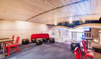 Second floor loft with arc planked ceiling, blue carpet, red chairs and small tables to work or socialize from.