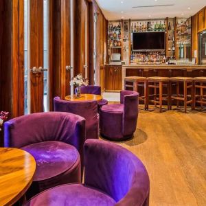 The hotel’s on-site bar, with hard floor and bright purple chairs.