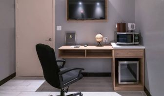 Workspace in a room at the Madison LES Hotel, including desk, chair, and microwave.