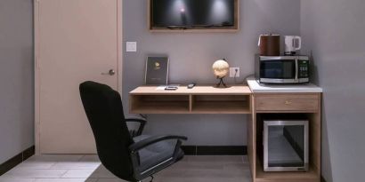 Workspace in a room at the Madison LES Hotel, including desk, chair, and microwave.