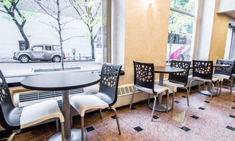 Econo Lodge Times Square’s breakfast area, with hard floor, tables for two, and large windows.