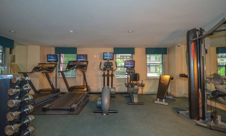 Fitness center with rack of weights, treadmills, and other exercise machinery.