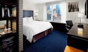 Guest room of the Hilton Fashion District, complete with king-sized bed and workspace desk and chair.