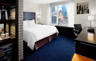 Guest room of the Hilton Fashion District, complete with king-sized bed and workspace desk and chair.