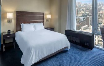 Guest room at the Hilton Fashion District, with double bed and view of the city.