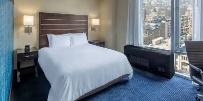 Guest room at the Hilton Fashion District, with double bed and view of the city.