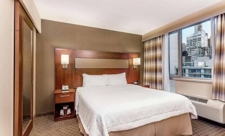 Double bed guest room in the Hampton Inn Manhattan Grand Central, NY, with large window offering a city view.