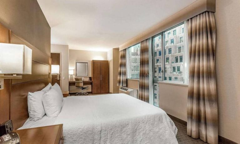 Guest room at the Hampton Inn Manhattan Grand Central, NY, with double bed, window, and workspace desk and chair.