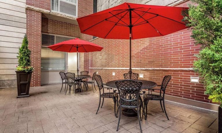 Patio area, with shaded tables and chairs, and nearby potted plants.