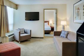 Guest room in the Radisson Hotel Kitchener Waterloo, with a lounge featuring chair, sofa, and TV.