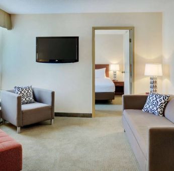 Guest room in the Radisson Hotel Kitchener Waterloo, with a lounge featuring chair, sofa, and TV.