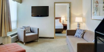 Guest room in the Radisson Hotel Kitchener Waterloo, with a lounge featuring chair, sofa, and TV.