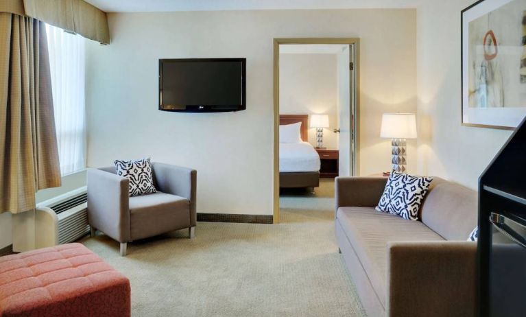 Guest room in the Radisson Hotel Kitchener Waterloo, with a lounge featuring chair, sofa, and TV.