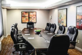 A meeting room with long wooden table and ten leather chairs around it.