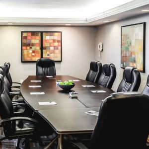 A meeting room with long wooden table and ten leather chairs around it.