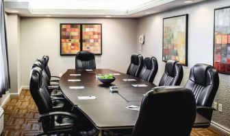 A meeting room with long wooden table and ten leather chairs around it.