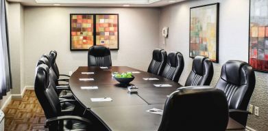 A meeting room with long wooden table and ten leather chairs around it.