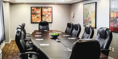 A meeting room with long wooden table and ten leather chairs around it.