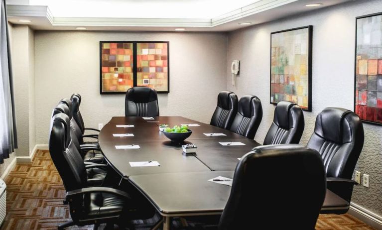 A meeting room with long wooden table and ten leather chairs around it.