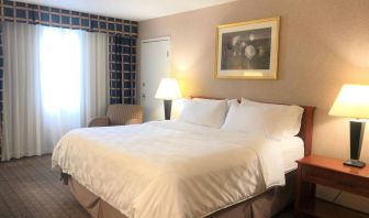 Double bed guest room in Holiday Inn Laval Montreal, with nearby chair and window.