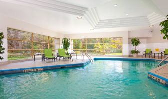 The hotel’s indoor swimming pool is brightly lit and has chairs and loungers by the side.