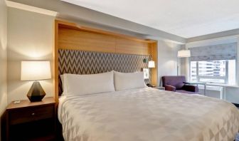 Double bed guest room in the Holiday Inn Ottawa Downtown Parliament Hill, with nearby chair and window.