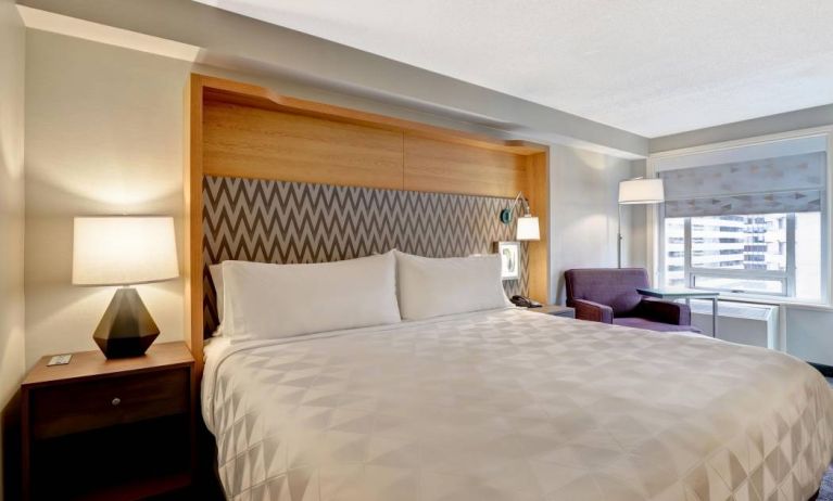 Double bed guest room in the Holiday Inn Ottawa Downtown Parliament Hill, with nearby chair and window.