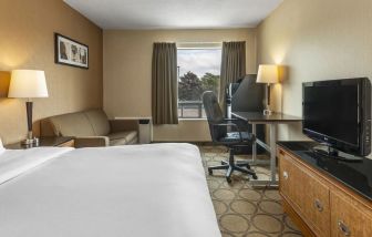 King bedroom with natural light , work space, and TV at Comfort Inn Airport East Ancienne-Lorette.