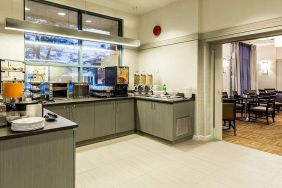 Food counter with pastry display container along with juice and coffee machine with seating lounge in adjacent room to eat, work, meet.