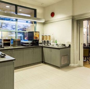 Food counter with pastry display container along with juice and coffee machine with seating lounge in adjacent room to eat, work, meet.