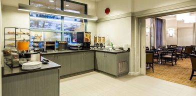 Food counter with pastry display container along with juice and coffee machine with seating lounge in adjacent room to eat, work, meet.