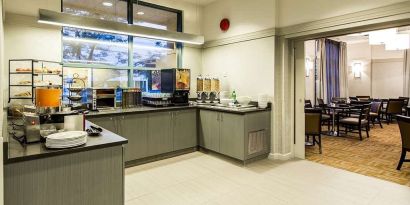 Food counter with pastry display container along with juice and coffee machine with seating lounge in adjacent room to eat, work, meet.