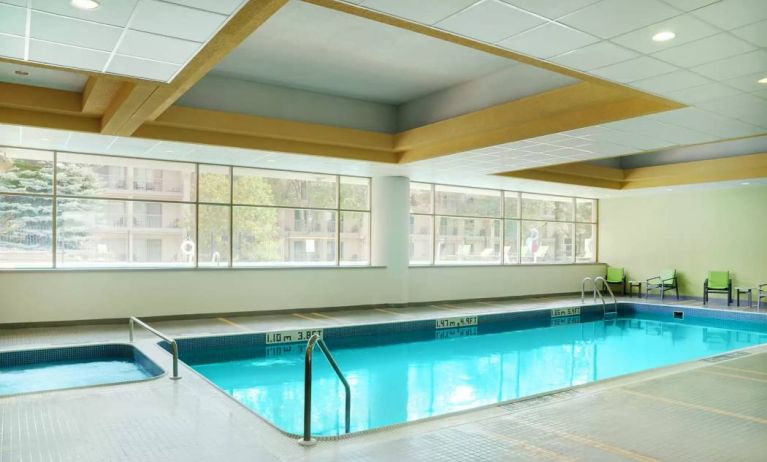 The hotel’s indoor pool is brightly lit and has chairs by the side.