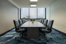 Hotel meeting room with a long wooden table and surrounding leather chairs.