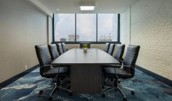 Hotel meeting room with a long wooden table and surrounding leather chairs.