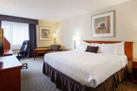 Guest room in Best Western North Bay, with large double bed, window, and armchair.