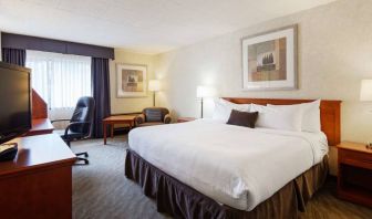 Guest room in Best Western North Bay, with large double bed, window, and armchair.