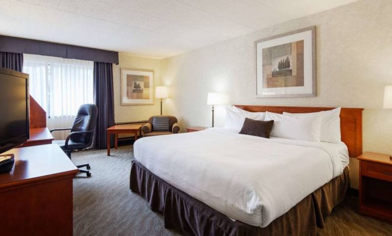 Guest room in Best Western North Bay, with large double bed, window, and armchair.