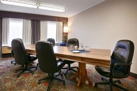 Hotel meeting with long wooden table and quintet of leather chairs around it.