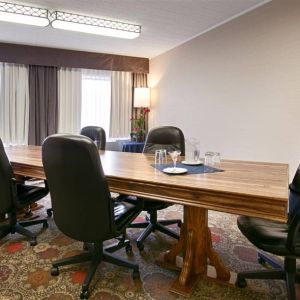 Hotel meeting with long wooden table and quintet of leather chairs around it.