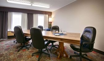 Hotel meeting with long wooden table and quintet of leather chairs around it.