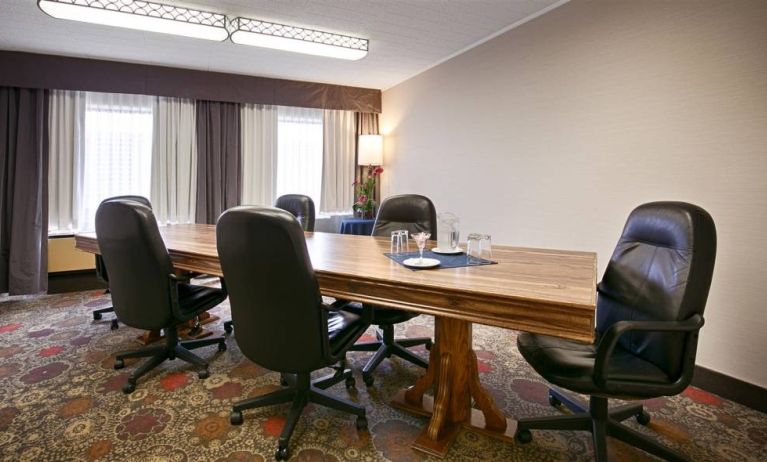 Hotel meeting with long wooden table and quintet of leather chairs around it.