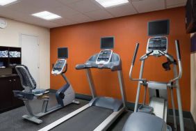 An exercise bicycle next to a treadmill and an elliptical machine in the Hampton Inn Manhattan - Madison Square Garden exercise room.